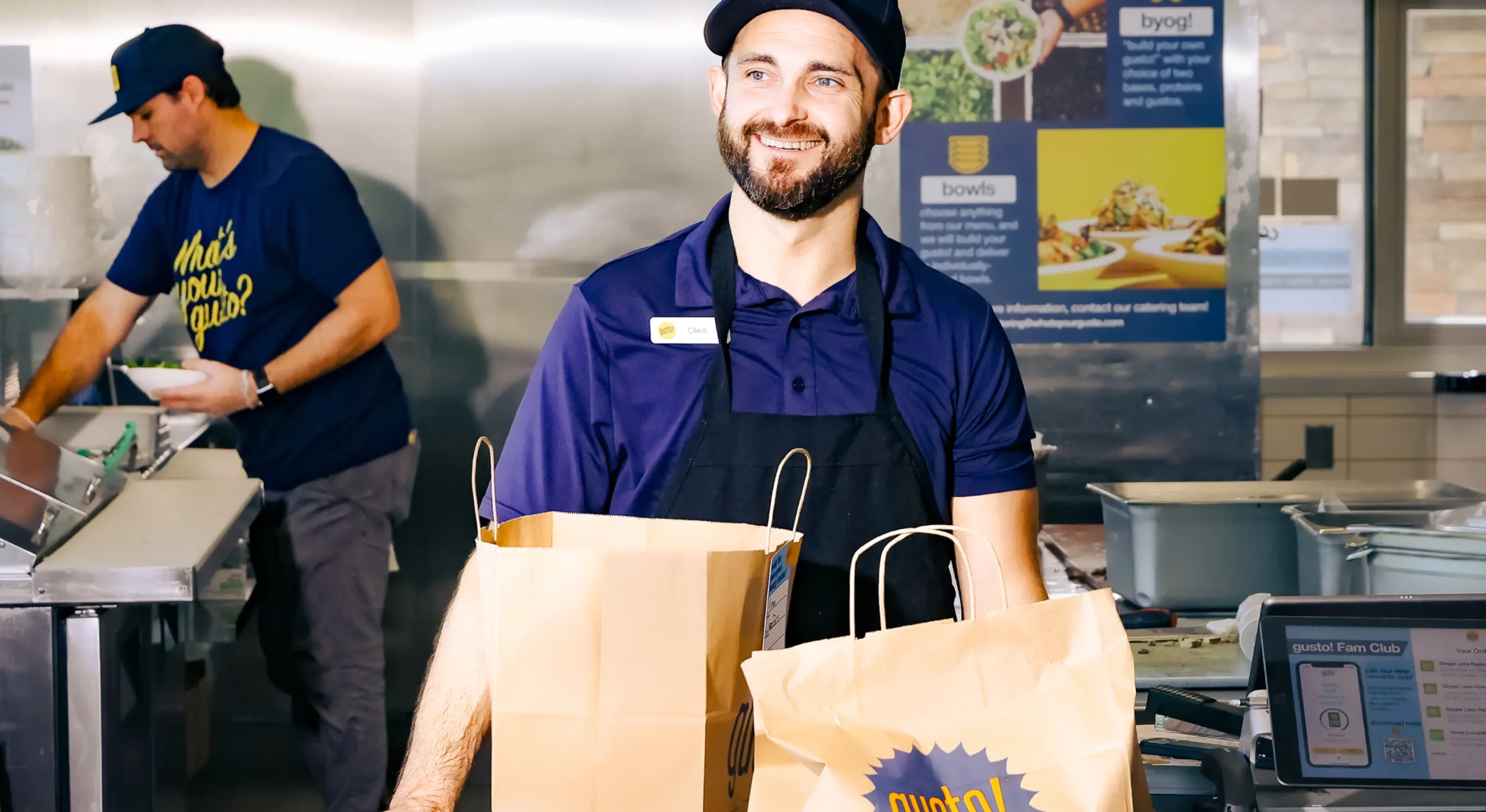 Smiling man serving takeout to go bag at quick serve restaurant